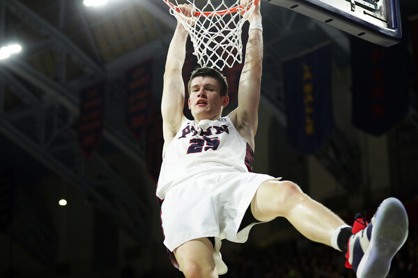 Junior forward A.J. Brodeur hangs on the rim after dunking the ball at the Palestra.