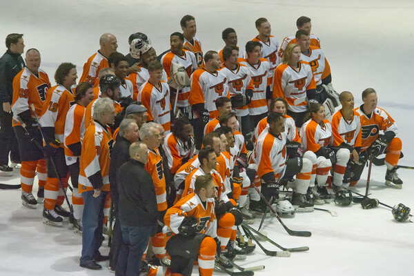 Members of Snider Hockey and Flyers Alumni pose on the ice for a group portrait