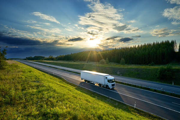 A white long-haul truck on an open highway. 