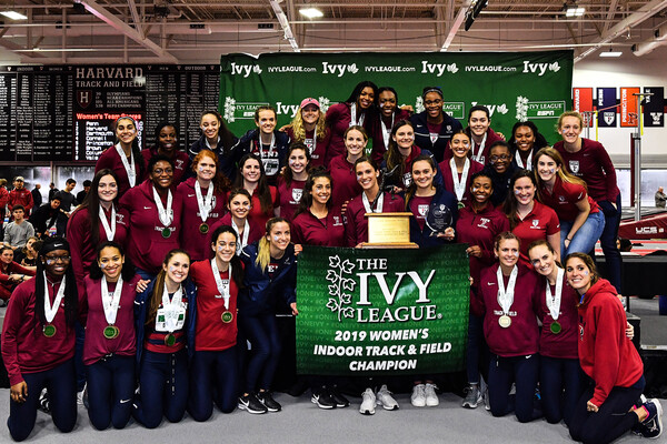 Members of the women's track and field team pose with the Heps indoor championship banner.