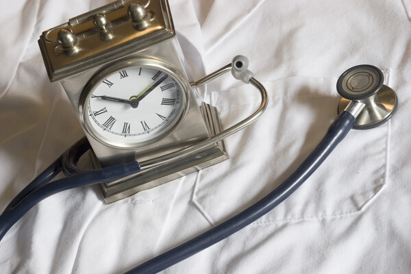 A clock and a stethoscope on top of a white lab coat.