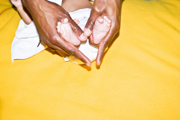  A pair of hands holding a newborn baby’s feet on a blanket