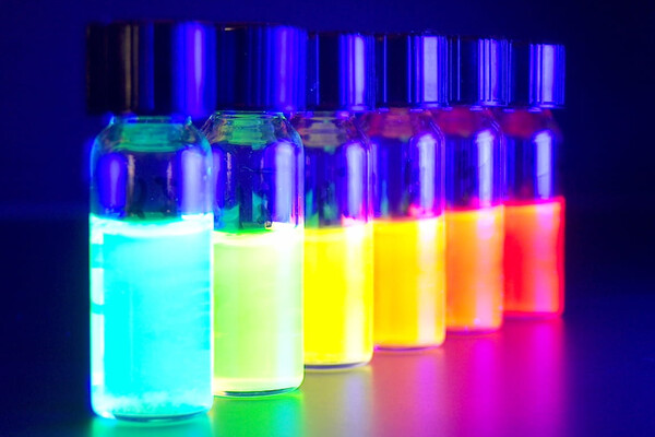 a line of test tubes filled with a rainbow of colored chemicals