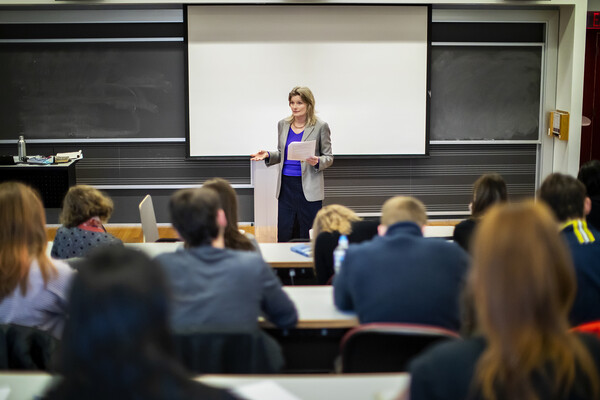 Jennifer Egan stands in front of classroom holding papers in hand.