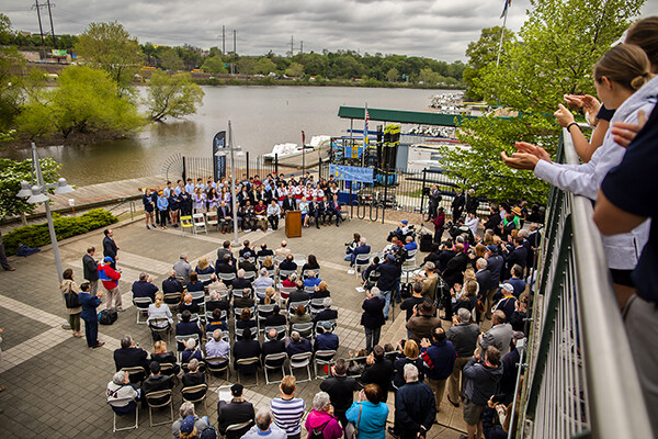 A crowd is seated on the walkway at the banks of the Schuylkill for a press conference.