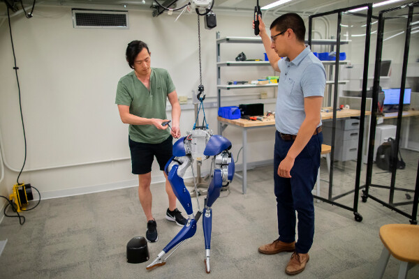 two people working on a set of robotic legs