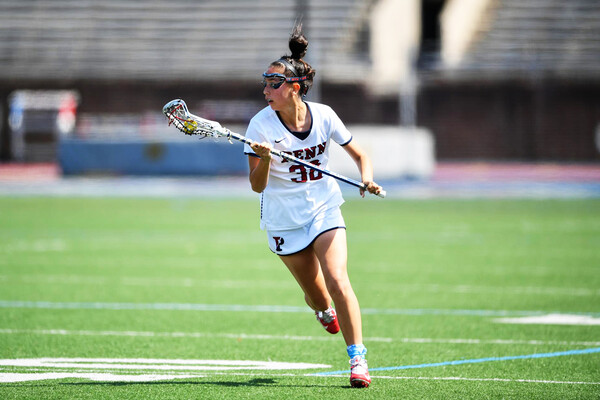 Michaela McMahon of the women's lacrosse runs up the field holding her stick.