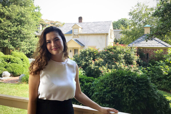 Student standing with historic buildings behind her. 