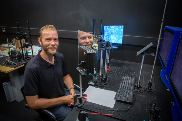 A person sitting in front of a computer and a machine that tests vision. 