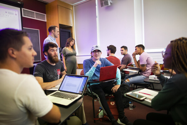 Students in a classroom seated in a circle respond with interest to a peer