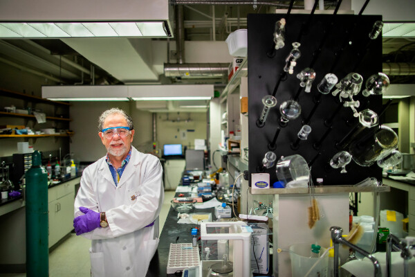 thomas mallouk poses in a laboratory surrounded by equipment and glassware