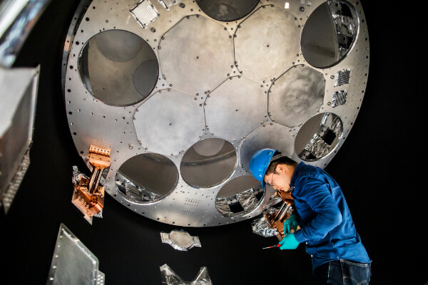 a person in a hard had working inside a large telescope detector