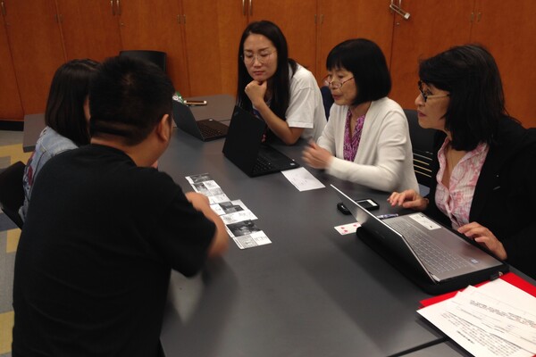 A group of people looking at photos on a table 