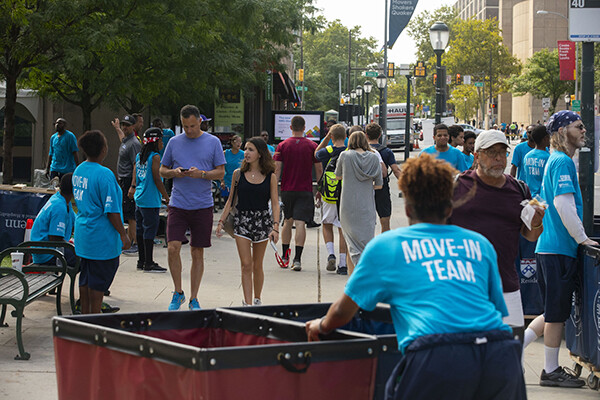 A busy sidewalk with pedestrians and Penn volunteers on Move-In day.