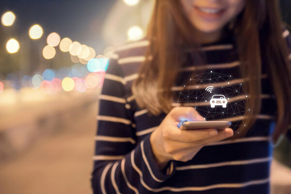 Person holding a cellphone with a lit up image of a car emanating from it. 