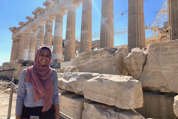 Students standing in front of a series of ancient columns and stones. 