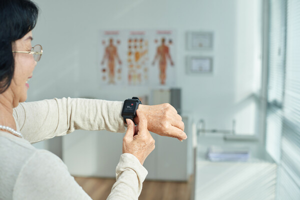 A person in a doctor's office checks their fitness tracker on their wrist.