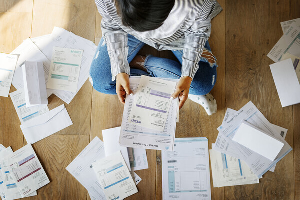 Person holding a sheet of paper listing bills due