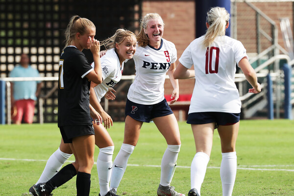A trio of players of the Penn women's soccer team celebrate on Rhodes Field against Towson.