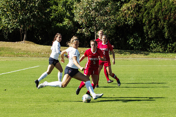 At Rhodes Field, a member of the women's soccer team dribbles the ball near a defender.