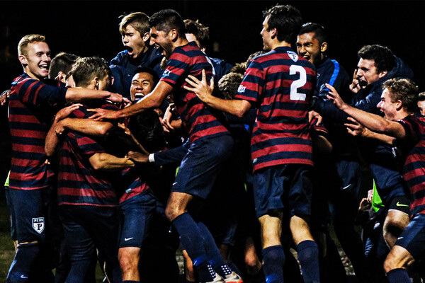 Jubilant players on the men's soccer team celebrate in a circle after defeating Yale.