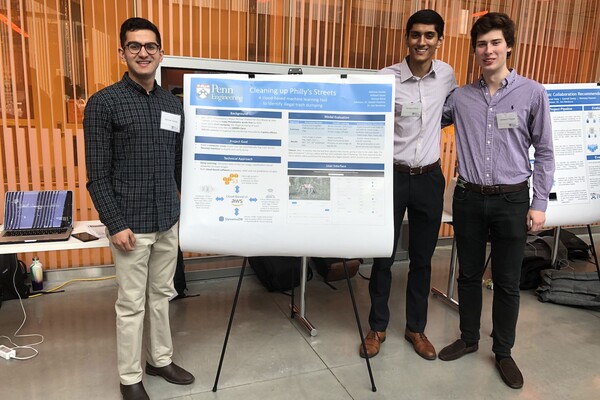 Three students stand next to a poster entitled "Cleaning Up Philly's Streets" which describes their project
