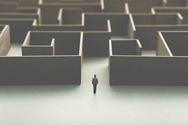 A figure stands at the entrance of a large human-scale maze, indicating memory and spatial navigation