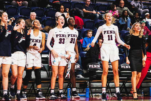 Members of the women's basketball stand near their bench at the Palestra cheering on their teammates.