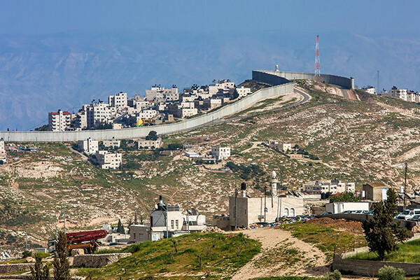 Palestinian town on the hill behind the Israeli separation barrier on the West Bank in Israel.