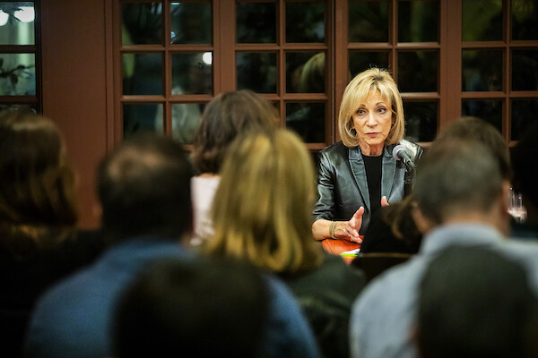NBC’s chief foreign affairs correspondent Andrea Mitchell sits at a table in front of a microphone, responding to a question at Kelly Writers House on Penn’s campus, as audience members look on.