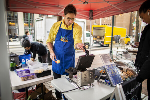 A person prepares to make a waffle in a farmer's market stand.