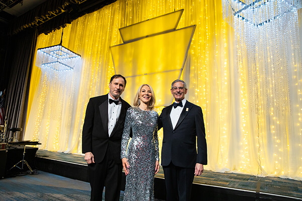 Penn president Amy Gutmann on stage at Pennsylvania Society Award dinner with husband and xxxx