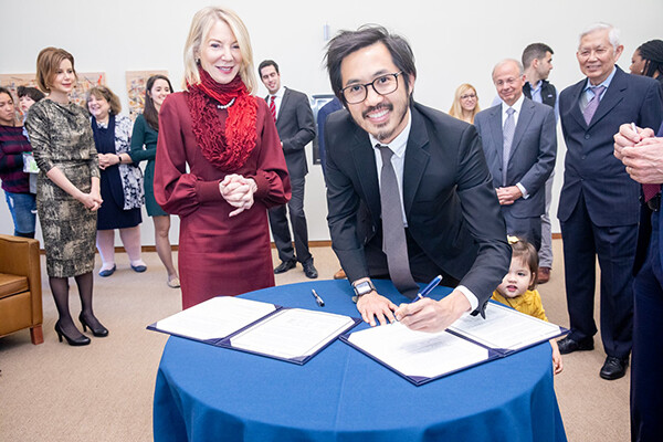 Amy Gutmann watches as Roderick Wong signs his gift to the Perelman School of Medicine.