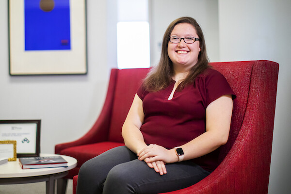 Woman with glasses sits in a lobby 