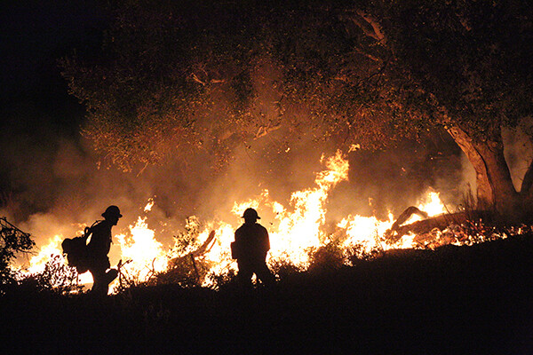 Fire crews tend to a using controlled burns at night to prevent further uncontrolled fires
