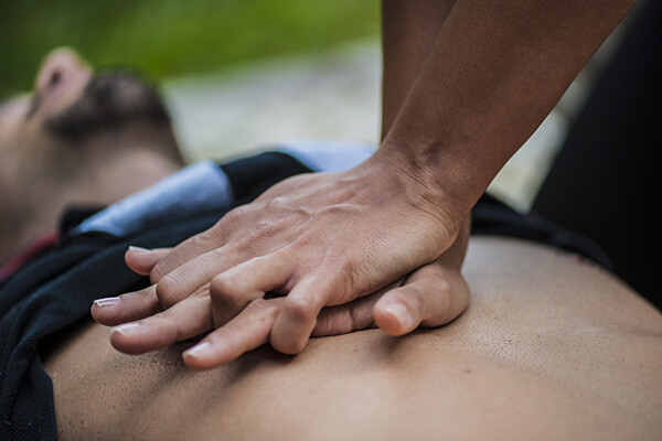 Closeup of hands on a person's chest performing chest compressions outdoors