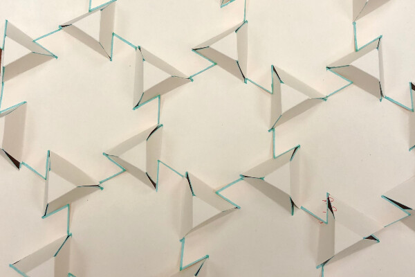 a pattern of raised triangles made out of paper with blue lines indicating flaps that reach out to neighboring structures