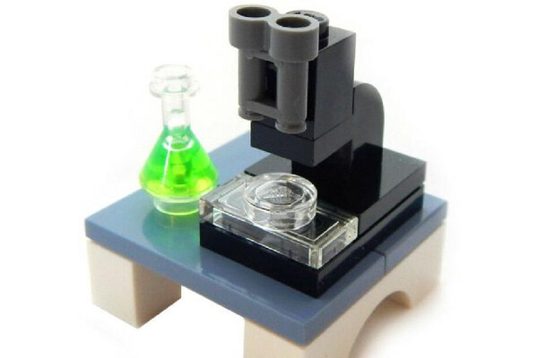 a lego set of a microscope on a table with a green vial next to it