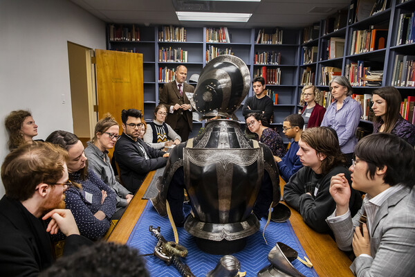 students gathered around a table looking at armor