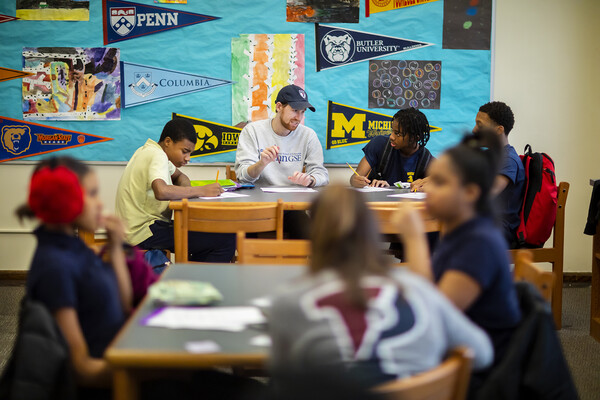 gse student mentoring at a table with college pennants behind