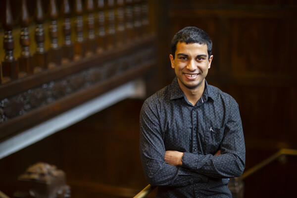 Student leaning on railing on staircase.