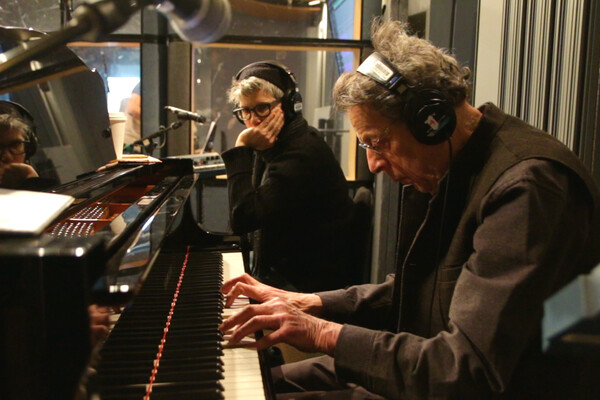 Philip Glass at piano with headphones