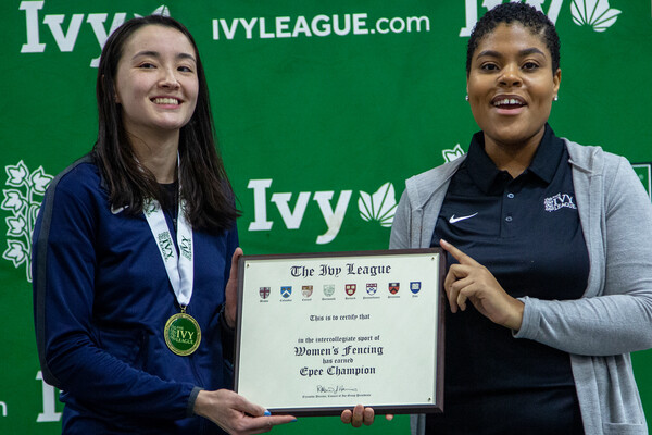 Chloe Daniel, left, receives a plaque celebrating her Ivy League individual epee championship from an Ivy League official.