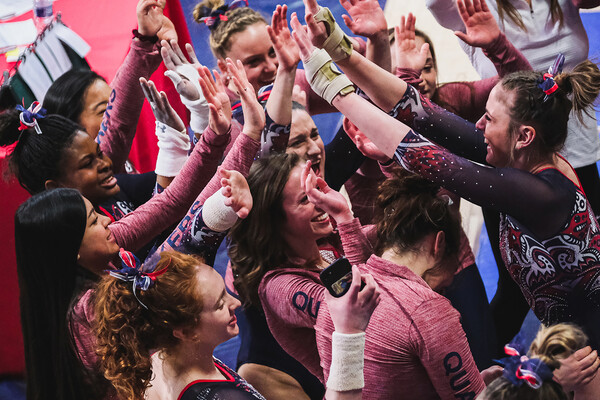 Members of the gymnastics team high-five and celebrate during a meet.