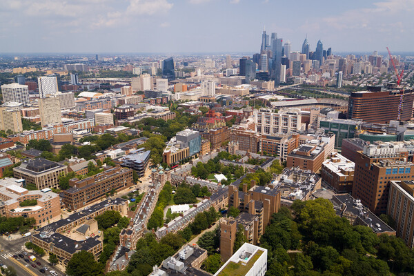 Aerial view of Penn campus buildings with Philadelphia skyline in background.