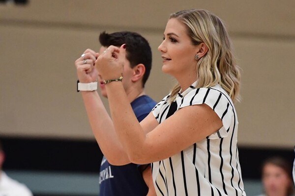 Wearing a white shirt with vertical black stripes, Meredith Schamun gestures with her hands during a game.
