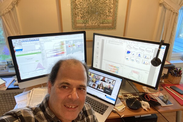 David Roos taking a selfie while teaching a class online, with scientific materials on the screen behind him