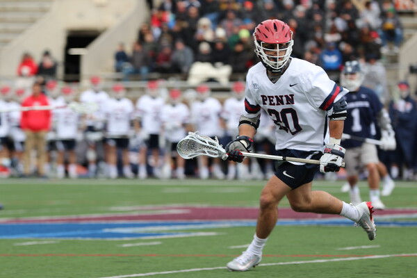 During a game, Adam Goldner moves across the field while carrying his lacrosse stick.