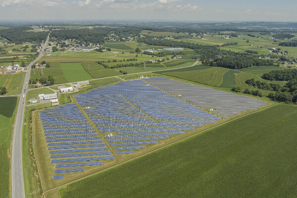 Aerial view of large greens landscape with solar panels set out over a large field. 
