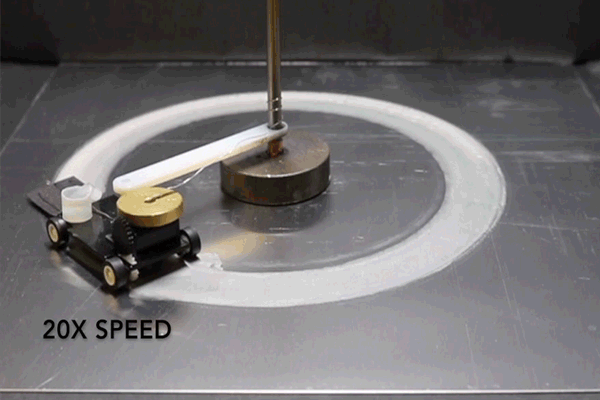 A robot resembling a toy car attached to a pole turns round and round over a surface covered in hydrogel.